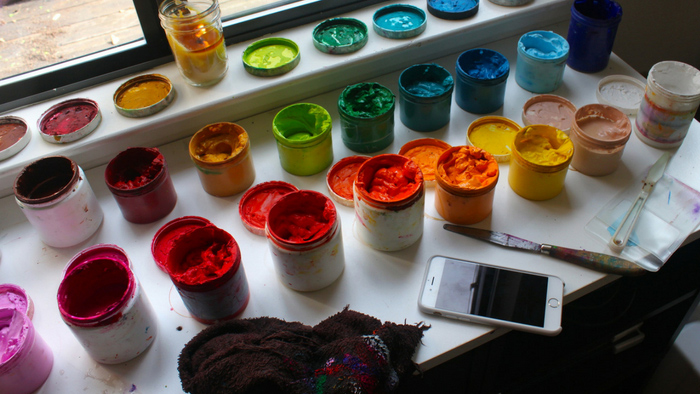 Brightly colored paints and a cell phone on a table